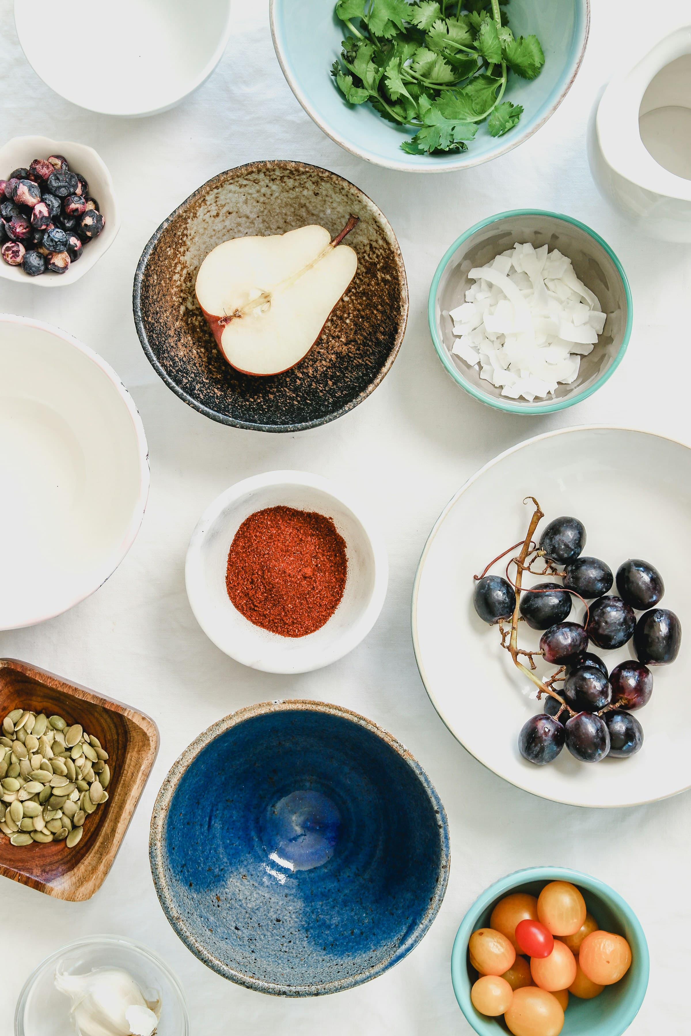 Overhead view of bowls filled with colorful spices, seeds, and botanicals