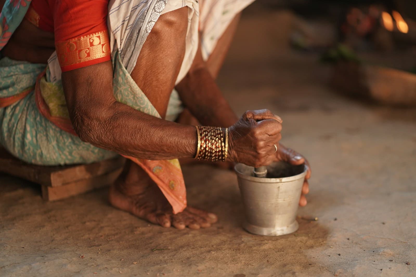 Weathered hands grinding spices with a mortar and pestle